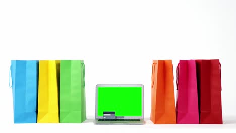 Multicolored-shopping-bags-and-laptop-on-white-background