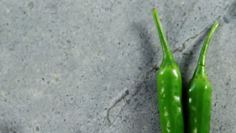 Two-green-chilli-pepper-on-concrete