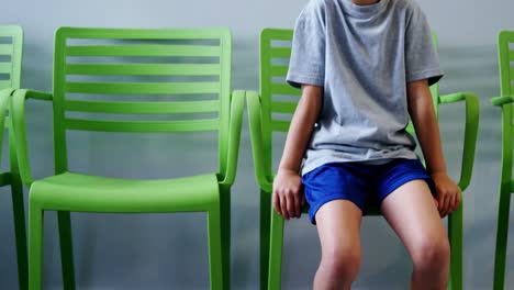 Upset-boy-sitting-on-chair-in-hospital-corridor