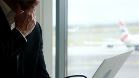Businessman-looking-at-laptop-at-airport