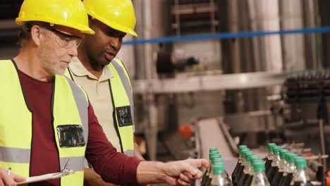 Workers-checking-juice-bottles-on-production-line