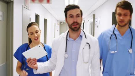 Team-of-doctors-interacting-while-walking-in-corridor