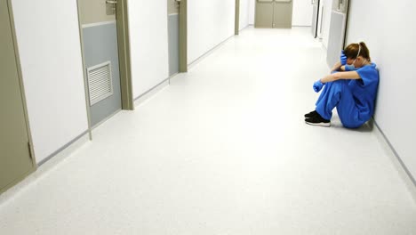 Tensed-female-doctor-sitting-in-corridor