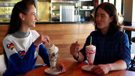 Happy-couple-interacting-with-each-other-while-having-milkshake