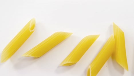 Penne-pasta-dispersed-on-white-background
