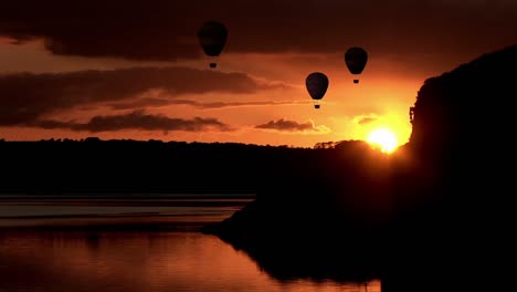 Hot-air-balloons-flying-over-lake-during-sunset