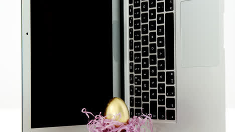 Golden-Easter-egg-and-laptop-on-white-background