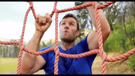Fit-man-climbing-a-net-during-obstacle-course