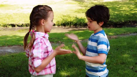 Two-siblings-playing-clapping-game-in-park