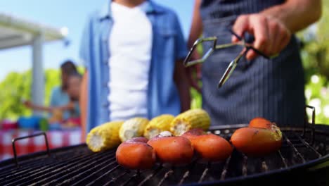 Father-and-son-grilling-sausages-and-corns-on-barbecue