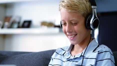 Boy-with-headphones-using-laptop-in-living-room
