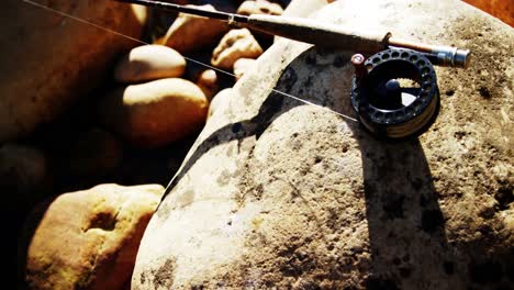 Fly-fishing-rod,-reel-and-hook-on-rock