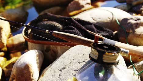 Fly-fishing-rod,-reel-and-tackle-box-on-rock