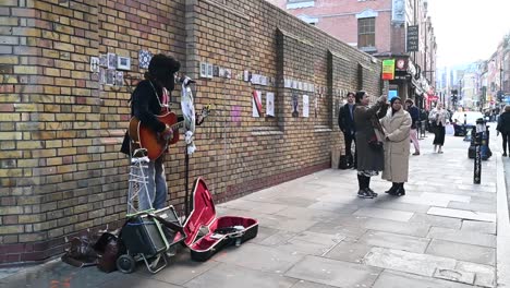 Playing-the-guitar-in-Brick-Lane,-London,-United-Kingdom