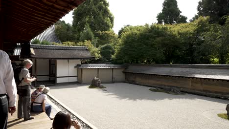 Tourists-Sitting-On-Veranda-Looking-At-Zen-Rock-Garden-At-Ryoanji-Temple-In-Kyoto