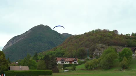 Paraglider-Lands-in-the-Field-near-the-Lake-Annecy-on-a-Cloudy-Day