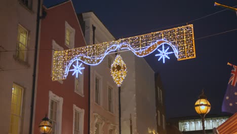 Low-Angle-Aufnahme-Von-Weihnachtslichtern,-Die-über-Einer-Straße-Im-Herzen-Von-Dublin,-Irland,-Hängen,-Mit-Hängender-Irischer-Flagge-In-Der-Nacht