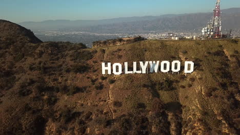 Aerial-tilt-shot-rising-in-front-of-the-Hollywood-sign,-sunset-in-Los-Angeles,-USA