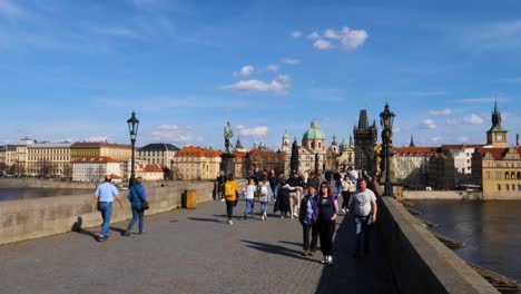 People-crossing-the-Charles-Bridge-in-Prague,-Czech-Republic
