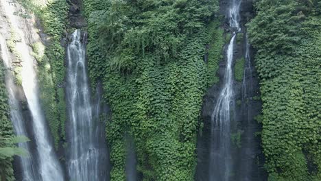 Aerial-rises-up-beautiful-waterfall-with-lush-green-foliage-on-cliff