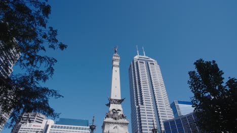 Indianapolis-soldiers-and-sailors-memorial-in-monument-circle-with-modern-high-rise-skyscrapers-reveal-from-behind-park-tree