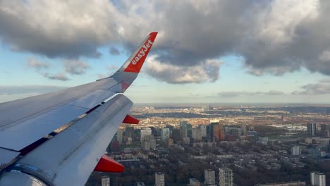 Blick-Auf-Den-Easyjet-Flugzeugflügel-Durch-Das-Flugzeugfenster,-Der-über-Eine-Stadt-In-Den-Niederlanden-Fliegt