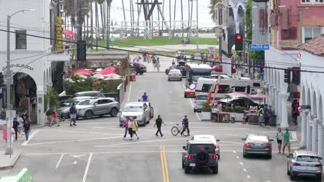 People-and-Cars-Moving-Under-Famous-Venice-Beach-Sign,-Static-Aerial-View,-Los-Angeles-CA-USA