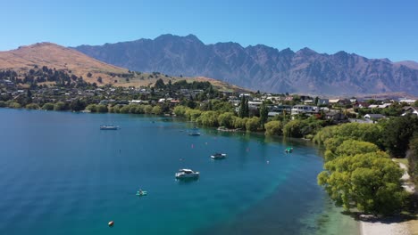UHD-Luftaufnahme-Von-Queenstown-Lakes,-Neuseeland,-An-Einem-Perfekten-Sonnigen-Tag-Mit-Kajaks-Im-Vordergrund