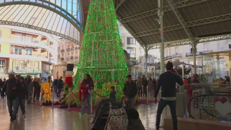 Shot-of-locals-walking-around-giant-Christmas-Tree-in-the-Mercado-de-Colon-in-Valencia,-Spain