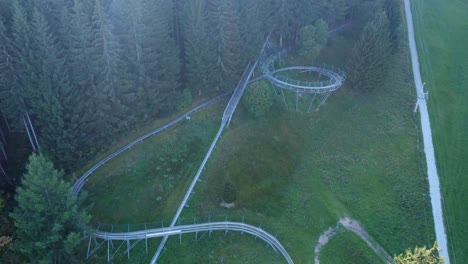Drone-shot-of-bobsleigh-on-wheels-riding-down-from-the-track-in-Swiss-mountains