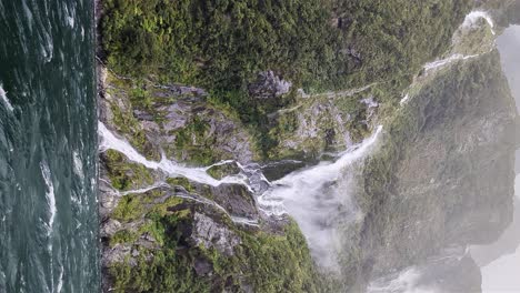 Doomsday-storm-blowing-falling-water-away-from-mountains-in-Milford-Sound,-vertical-view