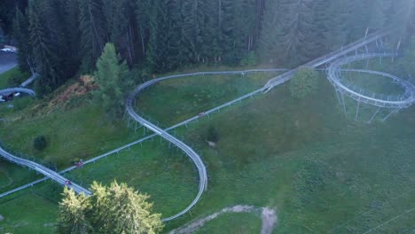 Pan-shot-with-Drone-of-bobsleigh-on-wheels-racing-down-with-high-speed-in-Swiss-mountains