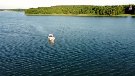 Motor-boat-driving-on-a-lake-surrounded-by-a-forest-during-summer-in-Brandenburg,-Germany