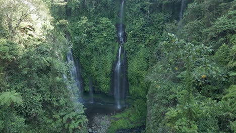 Aerial-approaches-beautiful-natural-waterfall,-dense-lush-Bali-jungle