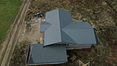 Luftaufnahme-Eines-Neuen-Modernen-Hauses-Mit-Dunkelblauem-Dach-In-Ländlicher-Landschaft-In-Riga,-Lettland