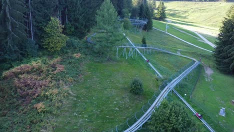 Drone-shot-of-bobsleigh-on-wheels-getting-up-to-hill-in-Swiss-mountains