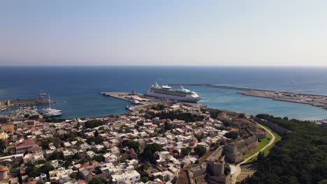 Drone-flies-over-the-Old-Town-of-Rhodes-towards-a-docked-cruise-ship-in-the-Kolona-Harbor