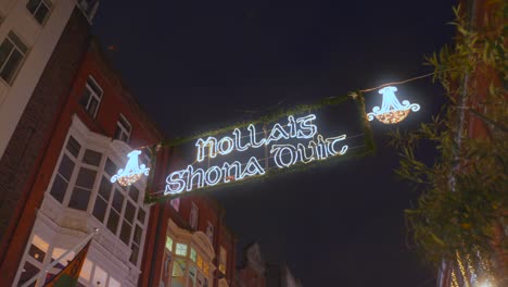 Low-angle-shot-of-Merry-Christmas-sign-written-in-Irish-Gaelic-language-in-Dublin,-Ireland-at-night-time
