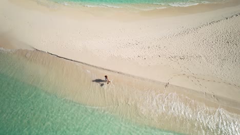 Aerial-shot-latin-woman-walk-on-white-sand-beach-lonely-exotic-caribbean-island,-Los-Roques