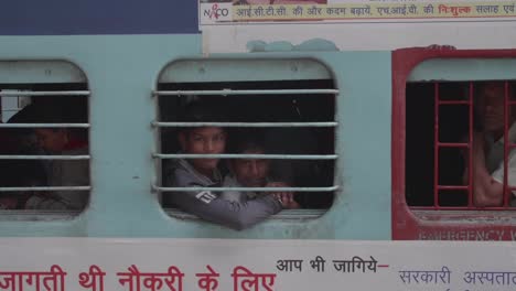 Local-Indian-family-and-elderly-male-watching-from-window-of-train-wagon