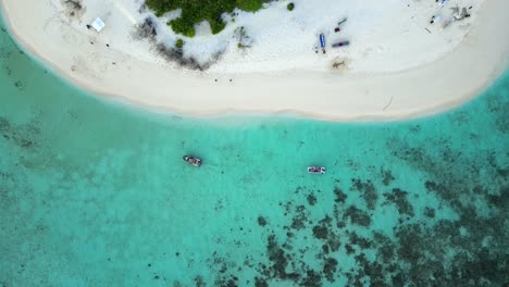 Vertical-aerial-view-of-small-boats-arriving-at-the-beach-on-Meeru-Fenfushi-desert-island,-Maldives,-Indian-Ocean