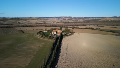 Drone-pullback-away-from-mansion-overlooking-sweeping-vista-of-Val-d'Orcia-Tuscany