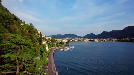 Establishing-aerial,-promenade-on-Lake-Como-toward-Como-village,-Italy