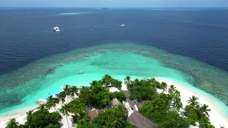 Aerial-view-of-Bathalaa-Island-and-its-buildings-and-palm-trees-together-with-the-surrounding-reef,-Maldives,-Indian-Ocean