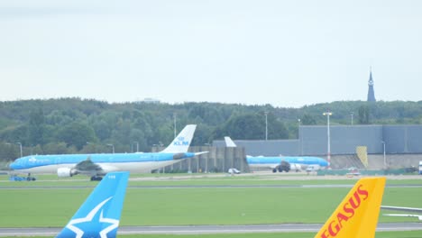 Ein-Großer-KLM-Airbus-Fährt-über-Ein-Außer-Kontrolle-Geratenes-Taxi-In-Richtung-Amsterdam-Schiphol,-Während-Ein-Anderes-Flugzeug-Abhebt
