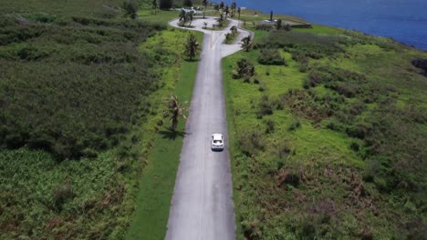 Hochkippbare-Drohnenaufnahme-Eines-Weißen-Autos,-Das-Entlang-Der-Banzai-Klippe-Auf-Der-Insel-Tinian-Fährt