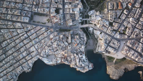 Top-down-aerial-timelapse-of-the-town-of-Polignano-a-Mare-during-the-morning-as-traffic-moves-across-the-roads