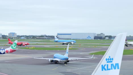 Schlepper-Schiebt-Ein-KLM-Flugzeug-Zurück,-Während-Ein-Anderes-Flugzeug-Abfliegt