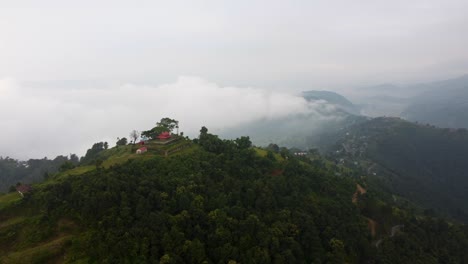 Filmische-Drohnenaufnahme-Eines-Asiatischen-Gebäudes-Auf-Dem-Toi-Des-Grünen-Berges-In-Nepal-–-Regenwaldhügellandschaft-Im-Hintergrund