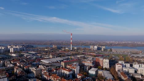 Aerial-flyover-of-the-buildings-in-Belgrade,-Serbia-with-a-chimney-smokestack-in-the-background